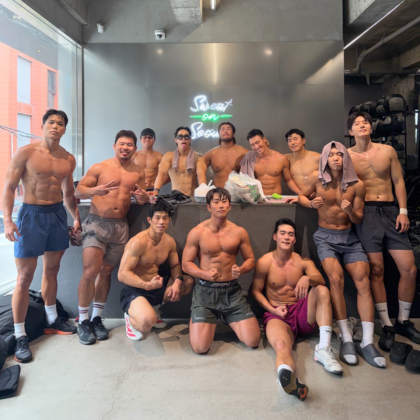 A group after training in front of the neon Sweat on Seoul sign